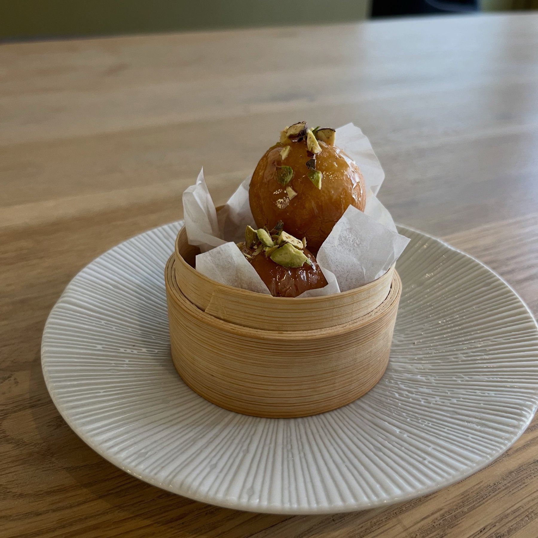 Dessert plated in a bamboo steamer on a white plate