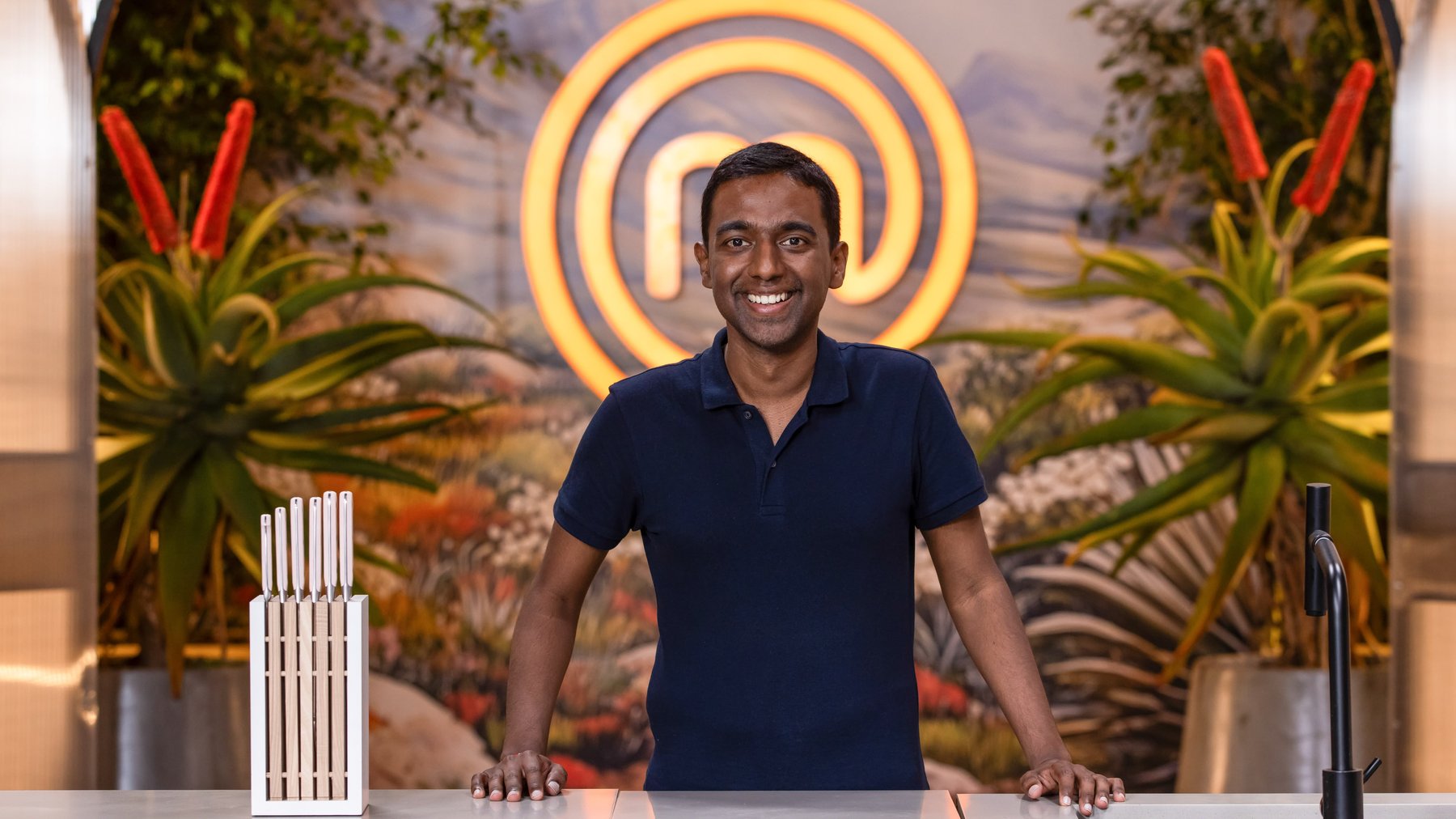 Jeshen Govender smiling in front of the MasterChef South Africa set